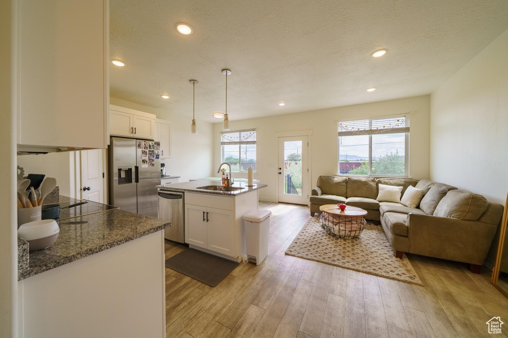 Kitchen featuring stainless steel appliances, a sink, white cabinets, light wood-style floors, and recessed lighting