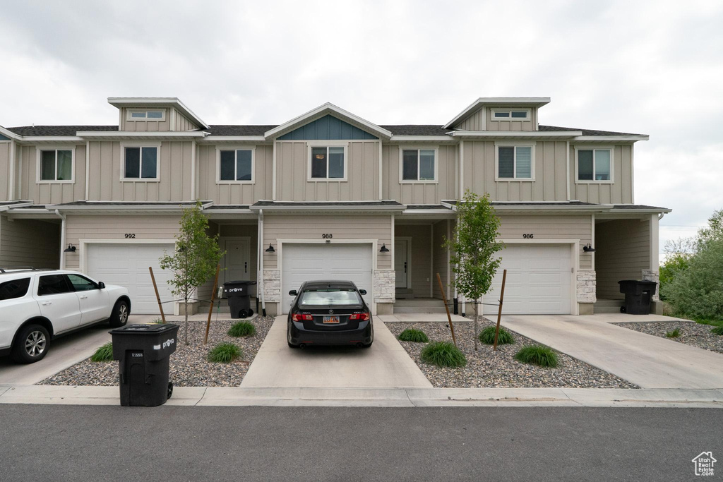 Townhome / multi-family property featuring a garage, board and batten siding, and driveway