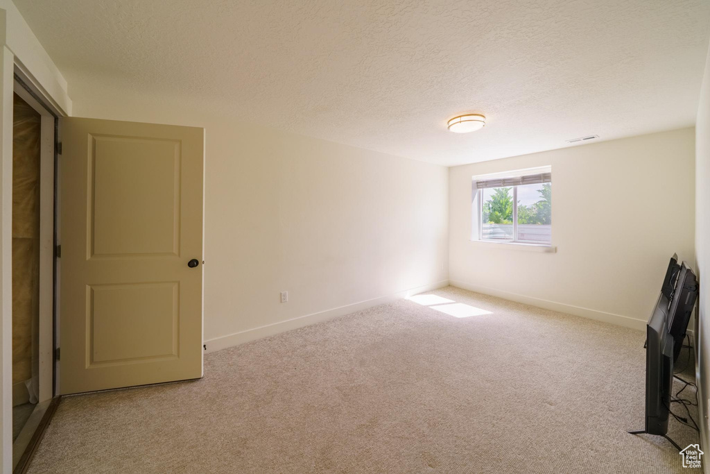Carpeted spare room featuring baseboards and a textured ceiling
