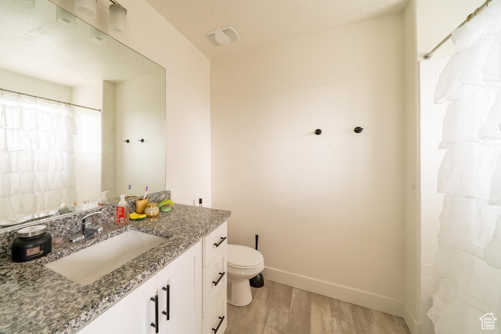 Full bathroom featuring wood finished floors, vanity, toilet, and baseboards