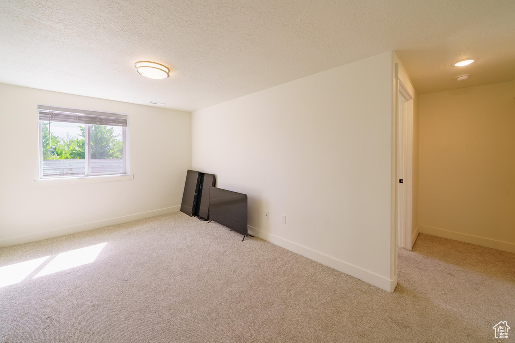 Carpeted empty room featuring baseboards and a textured ceiling