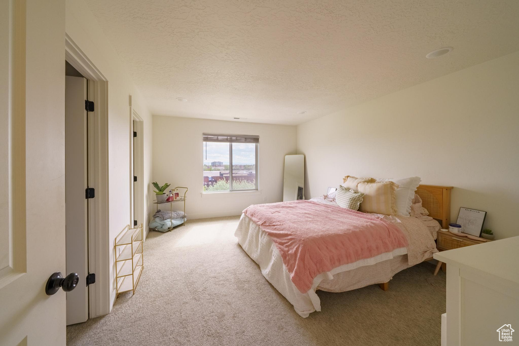 Bedroom featuring light carpet and a textured ceiling