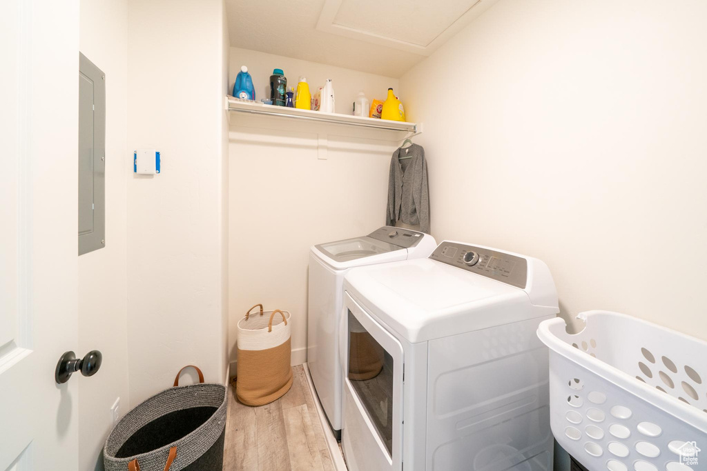 Washroom featuring washing machine and dryer, wood finished floors, and electric panel