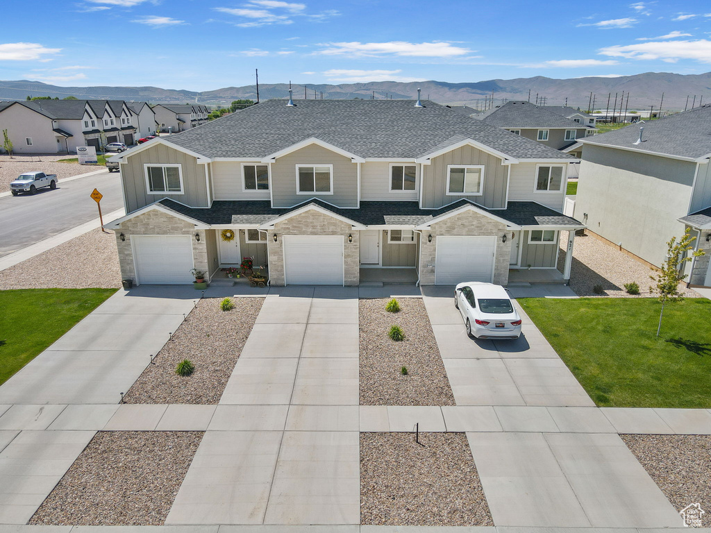 Townhome / multi-family property featuring board and batten siding, a mountain view, concrete driveway, and a shingled roof