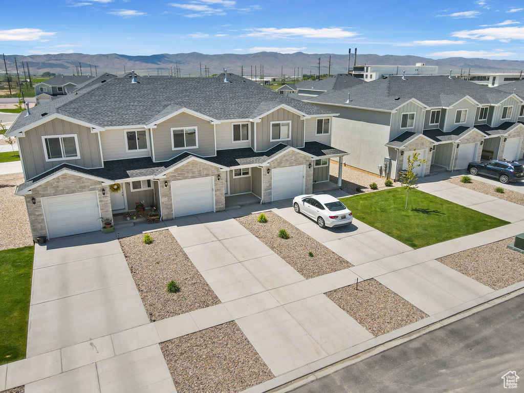 Townhome / multi-family property featuring a mountain view, board and batten siding, driveway, stone siding, and roof with shingles