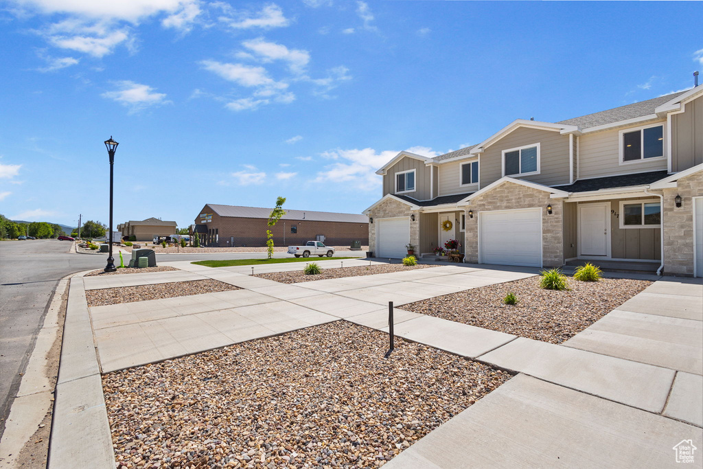 Townhome / multi-family property with concrete driveway, a garage, and a shingled roof