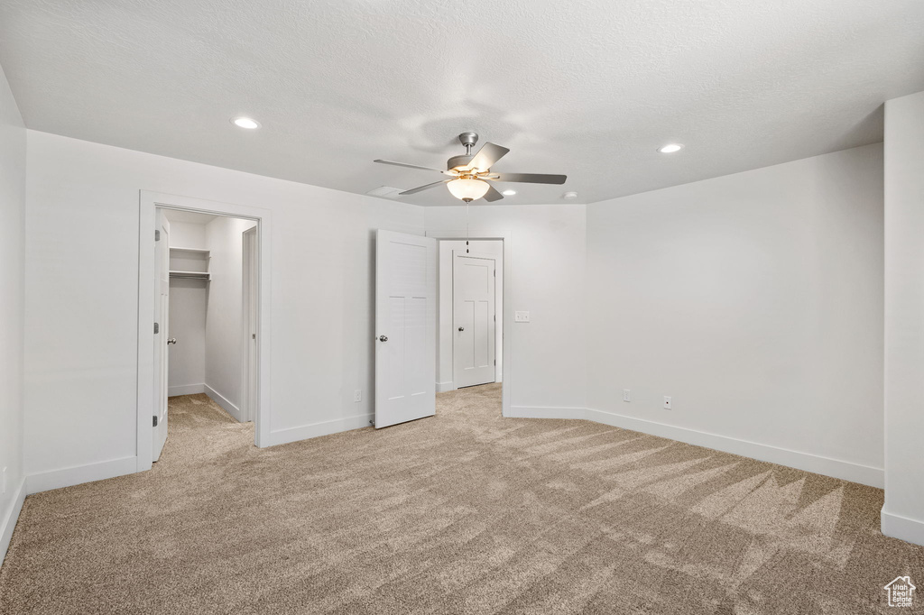 Unfurnished bedroom with light colored carpet, baseboards, recessed lighting, a spacious closet, and a ceiling fan