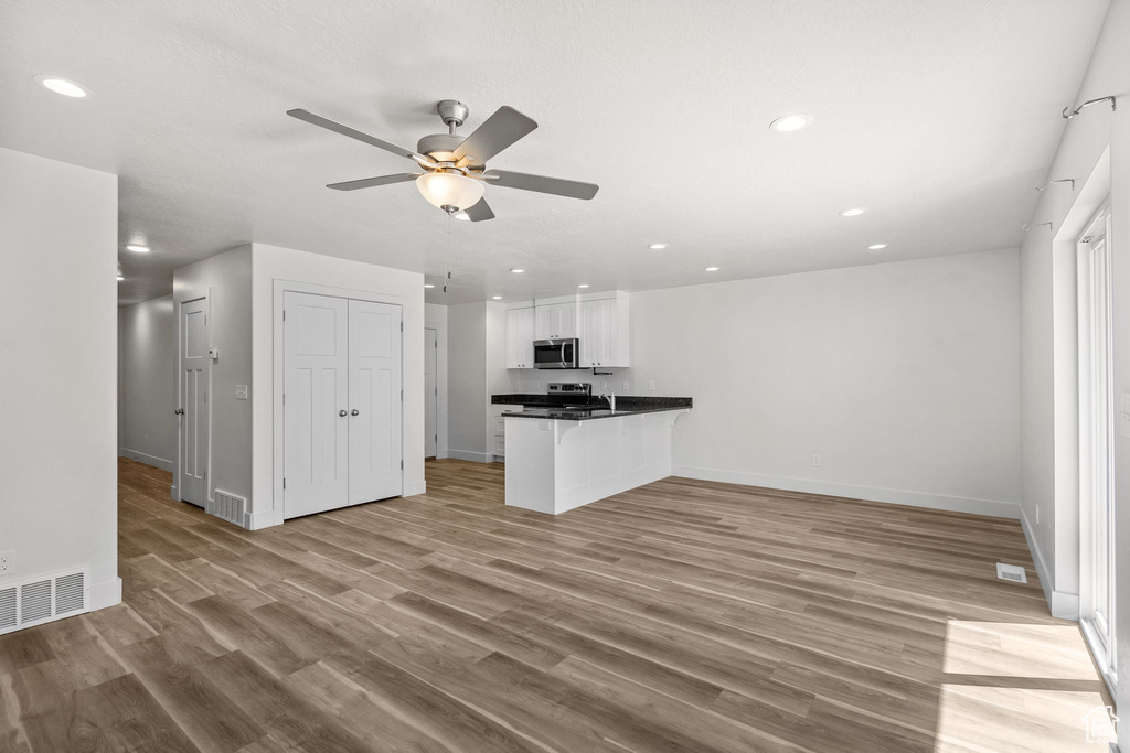 Unfurnished living room with a ceiling fan, light wood-style floors, baseboards, and recessed lighting