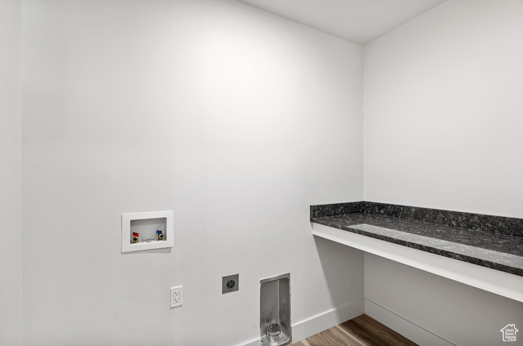 Washroom with electric dryer hookup, washer hookup, dark wood-style flooring, baseboards, and a desk
