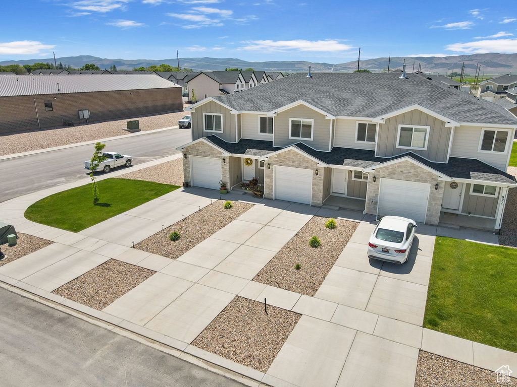 View of property featuring board and batten siding, a mountain view, a shingled roof, and concrete driveway