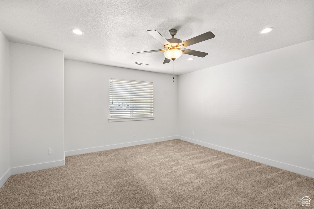 Empty room featuring ceiling fan, light colored carpet, baseboards, recessed lighting, and a textured ceiling