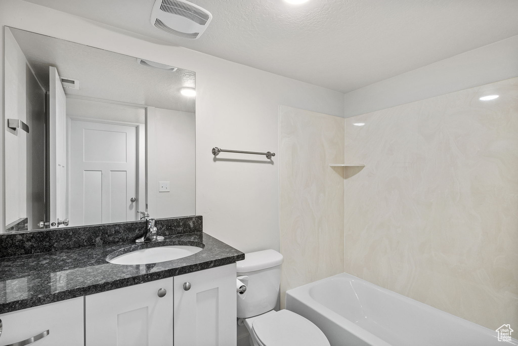 Bathroom featuring toilet, vanity, a textured ceiling, and tub / shower combination