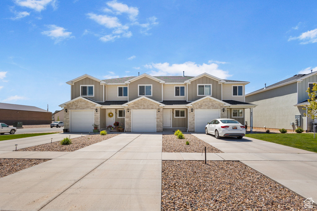 View of property featuring concrete driveway, board and batten siding, an attached garage, and stone siding