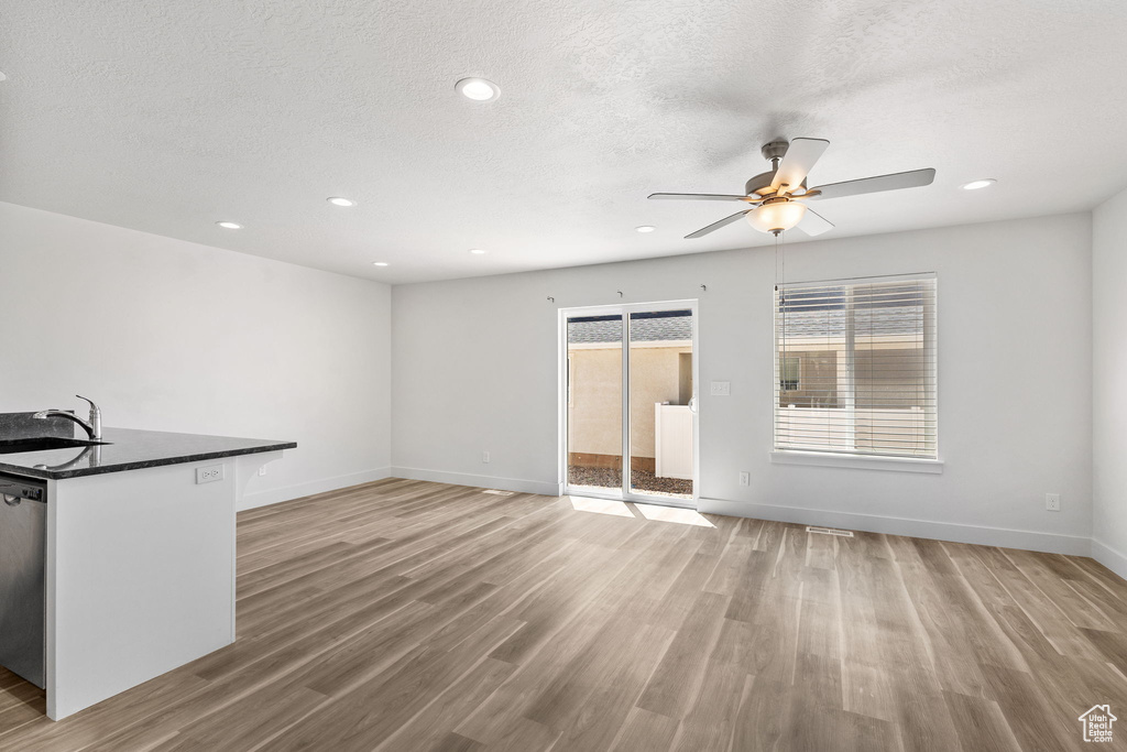 Unfurnished living room with a ceiling fan, light wood-style flooring, baseboards, a sink, and recessed lighting