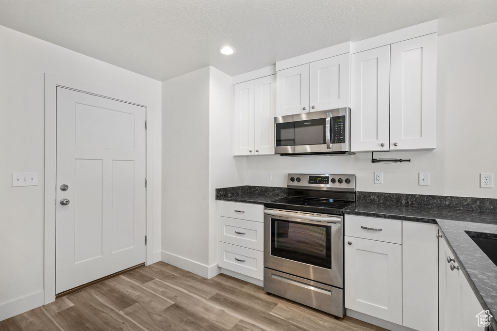 Kitchen featuring appliances with stainless steel finishes, white cabinetry, light wood-type flooring, recessed lighting, and baseboards