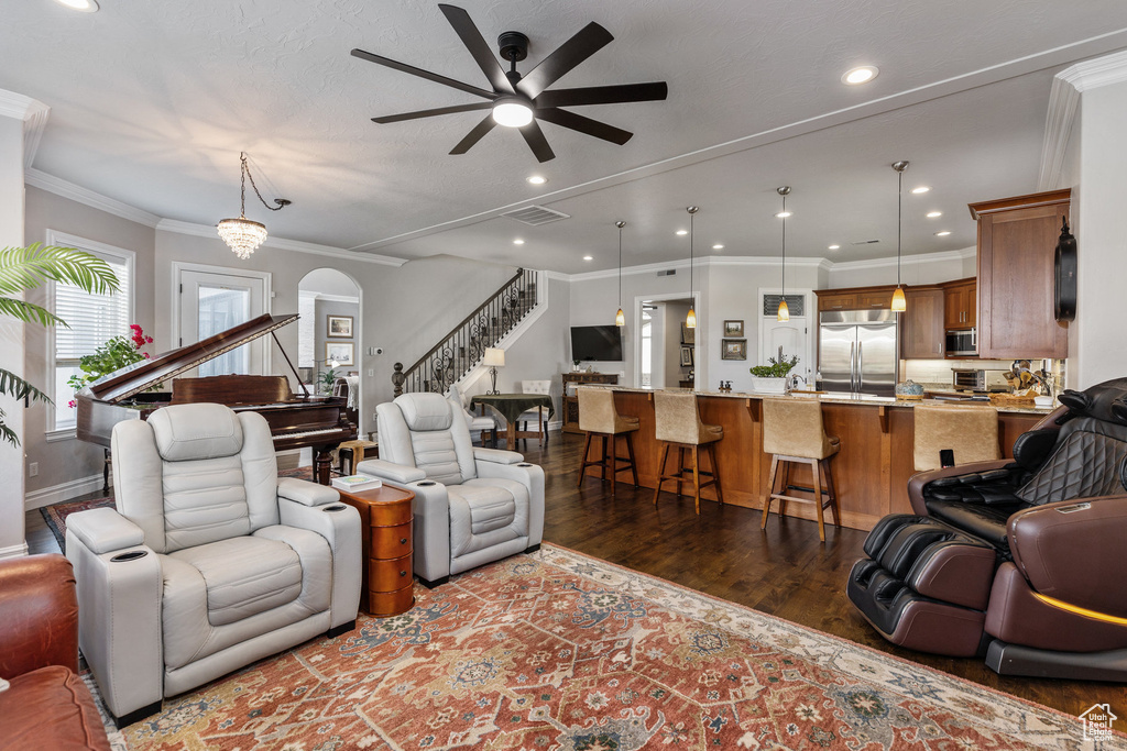 Living room with dark wood-style flooring, ceiling fan, stairs, recessed lighting, and arched walkways