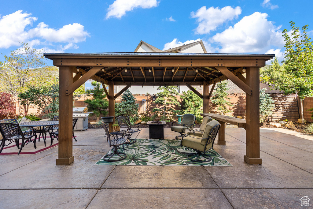 View of patio with a gazebo, a fire pit, and outdoor dining space