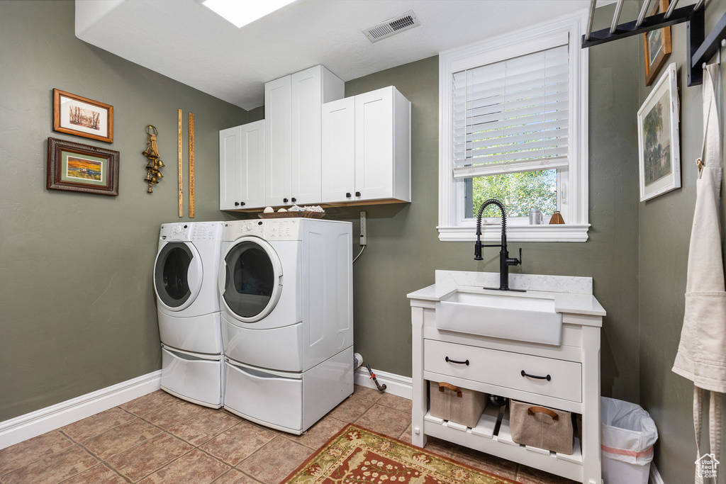 Washroom featuring independent washer and dryer, cabinet space, baseboards, and light tile patterned flooring