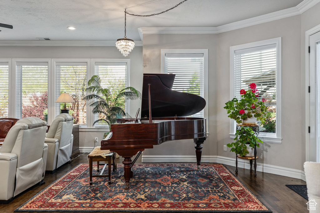 Living area with healthy amount of natural light, crown molding, baseboards, and dark wood finished floors