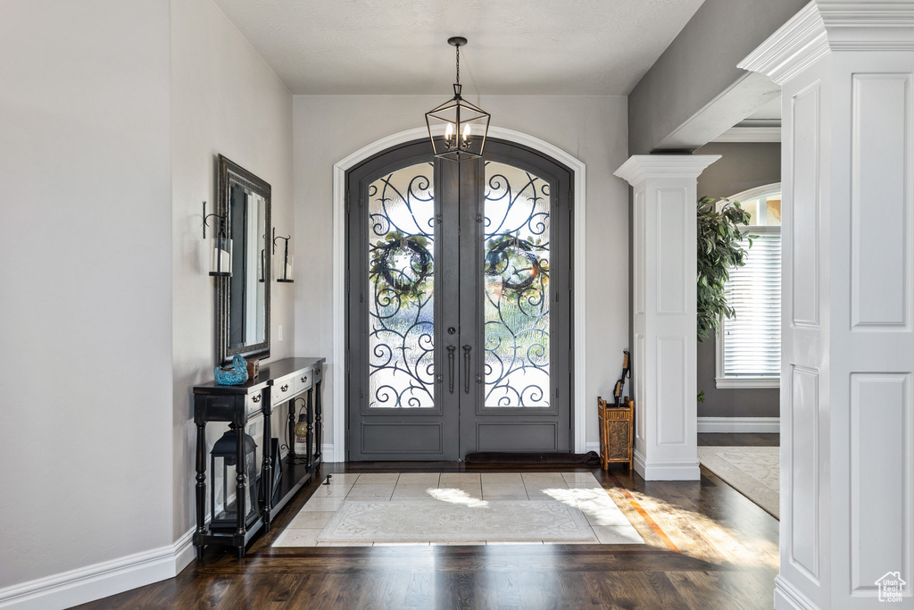 Foyer featuring french doors, arched walkways, a chandelier, and wood finished floors