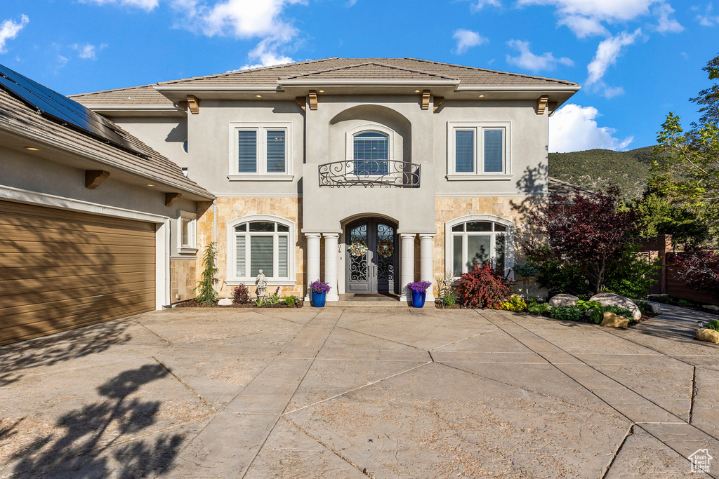 Mediterranean / spanish-style house with a balcony, french doors, stucco siding, driveway, and a tiled roof