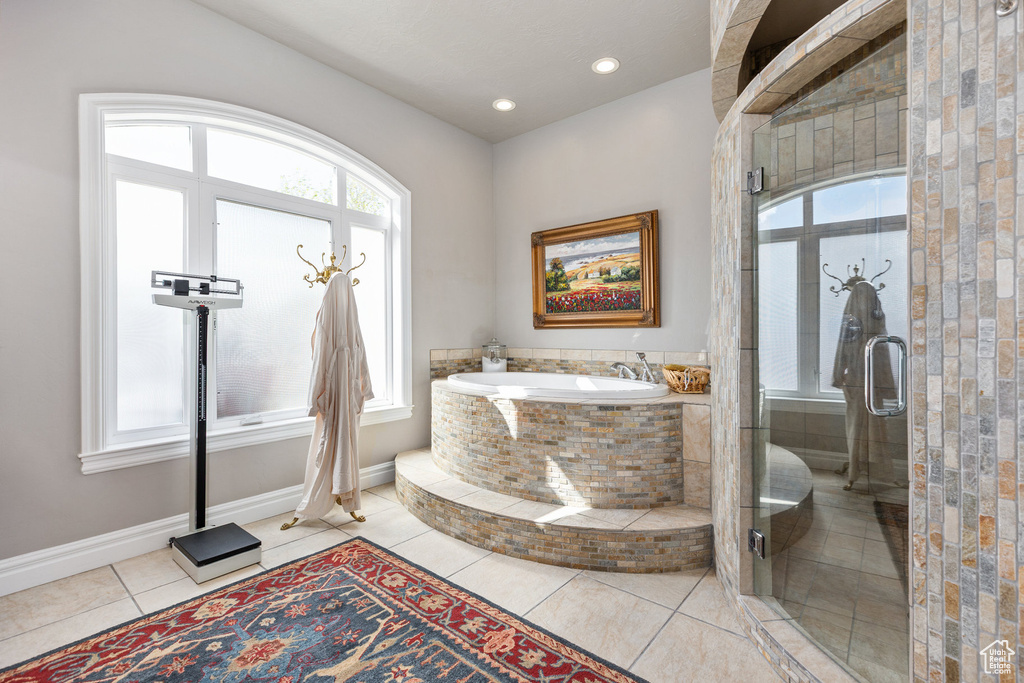 Bathroom featuring tile patterned flooring, healthy amount of natural light, a bath, a stall shower, and recessed lighting