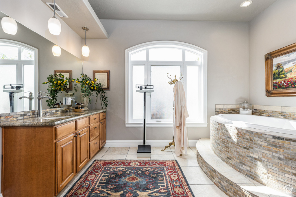 Bathroom with vanity, a garden tub, baseboards, and tile patterned floors