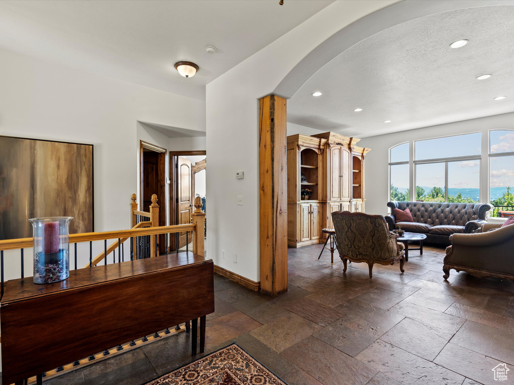 Corridor featuring arched walkways, recessed lighting, stone tile flooring, and baseboards