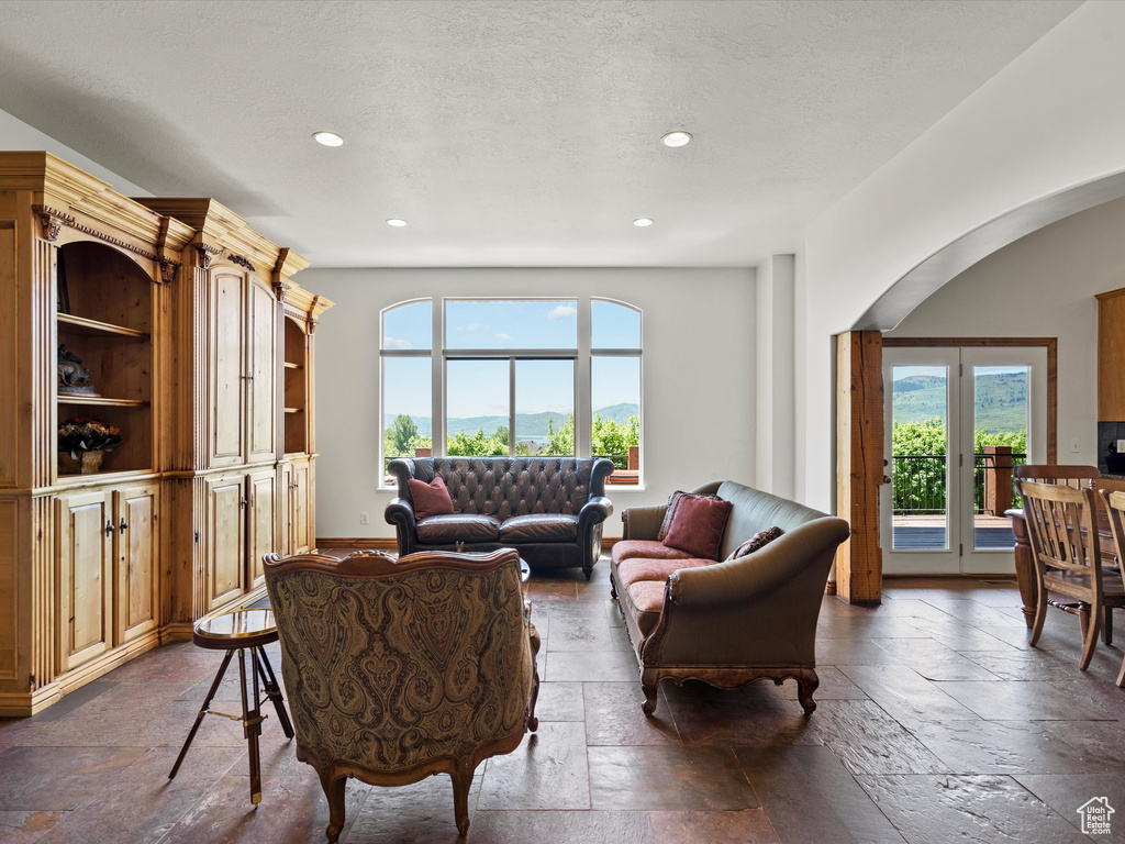 Living room with stone tile flooring, arched walkways, recessed lighting, and a textured ceiling
