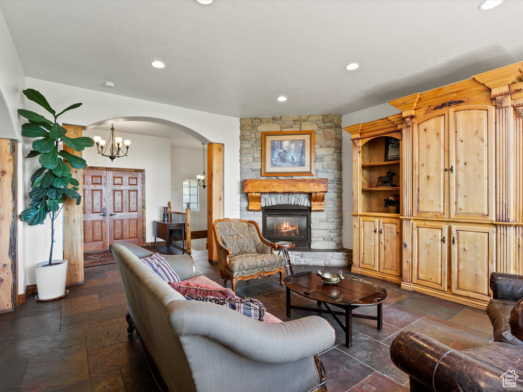 Living area featuring stone tile flooring, arched walkways, recessed lighting, a fireplace, and baseboards