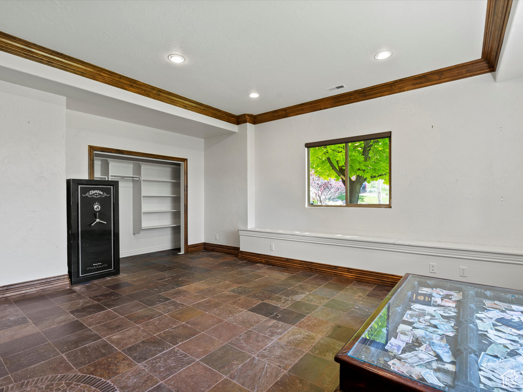 Spare room featuring crown molding, baseboards, stone tile flooring, and recessed lighting
