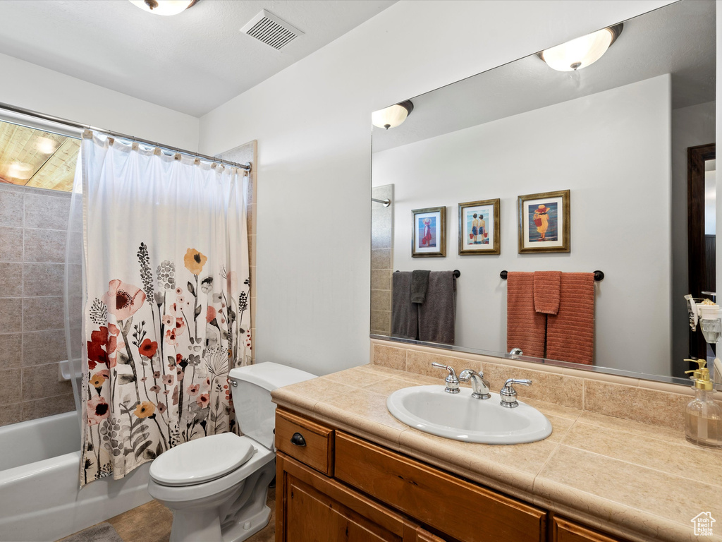 Full bath with toilet, vanity, and shower / bath combo with shower curtain