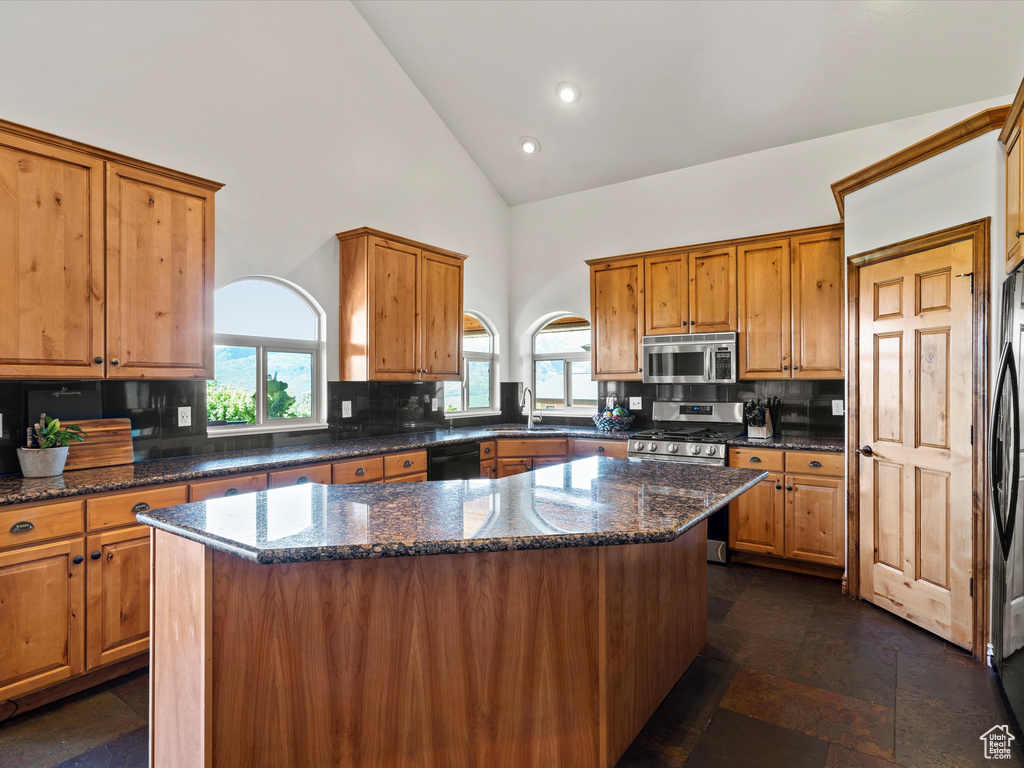 Kitchen featuring stainless steel appliances, high vaulted ceiling, a sink, brown cabinets, and recessed lighting