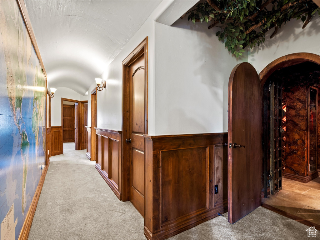 Hall with a wainscoted wall, carpet floors, and lofted ceiling