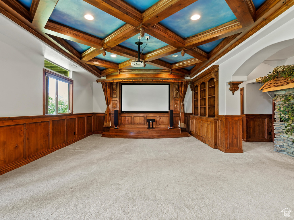 Carpeted home theater room featuring wainscoting, coffered ceiling, beam ceiling, recessed lighting, and a decorative wall