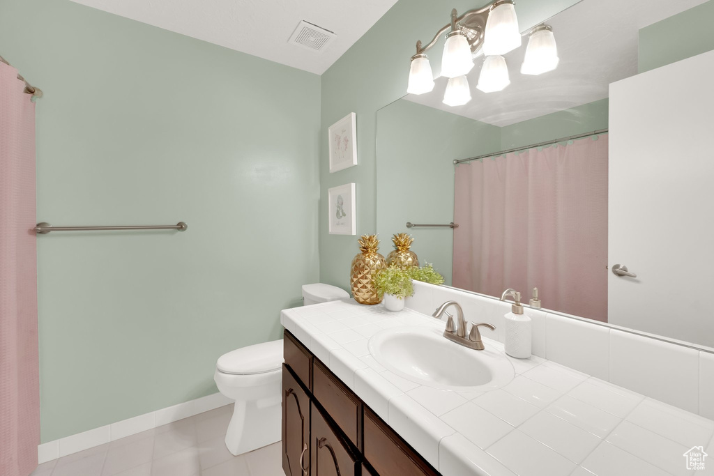 Bathroom featuring toilet, vanity, baseboards, and tile patterned flooring