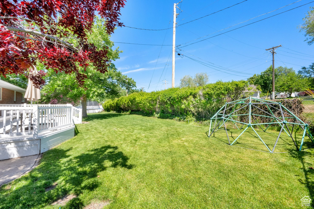 View of grassy yard featuring a deck