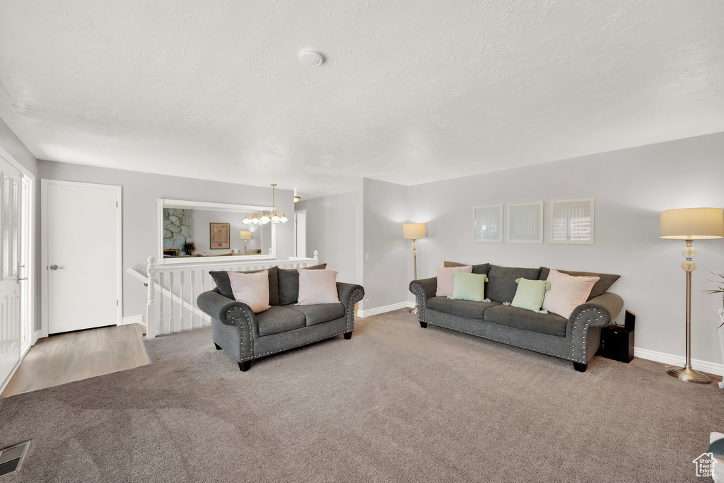 Carpeted living area with a chandelier, baseboards, and a textured ceiling