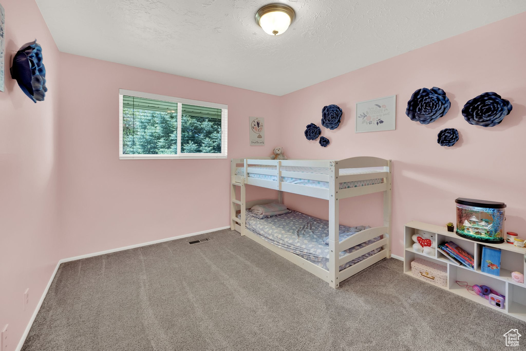 Carpeted bedroom featuring a textured ceiling and baseboards