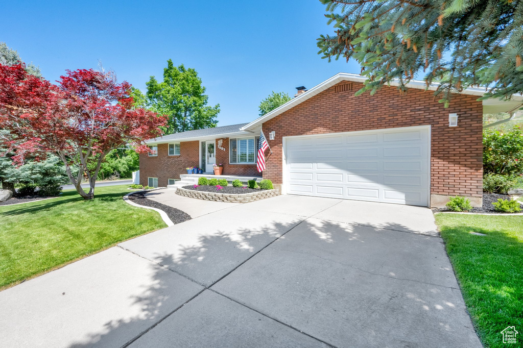Ranch-style house with brick siding, concrete driveway, a garage, and a front lawn