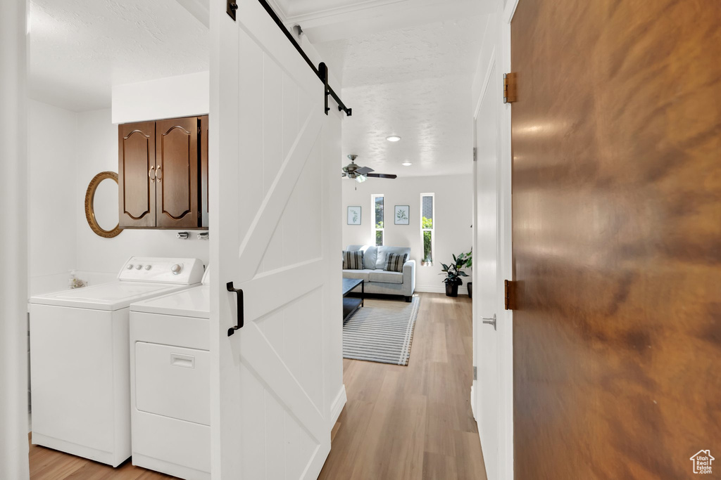 Hall with a barn door, separate washer and dryer, and light wood-style flooring