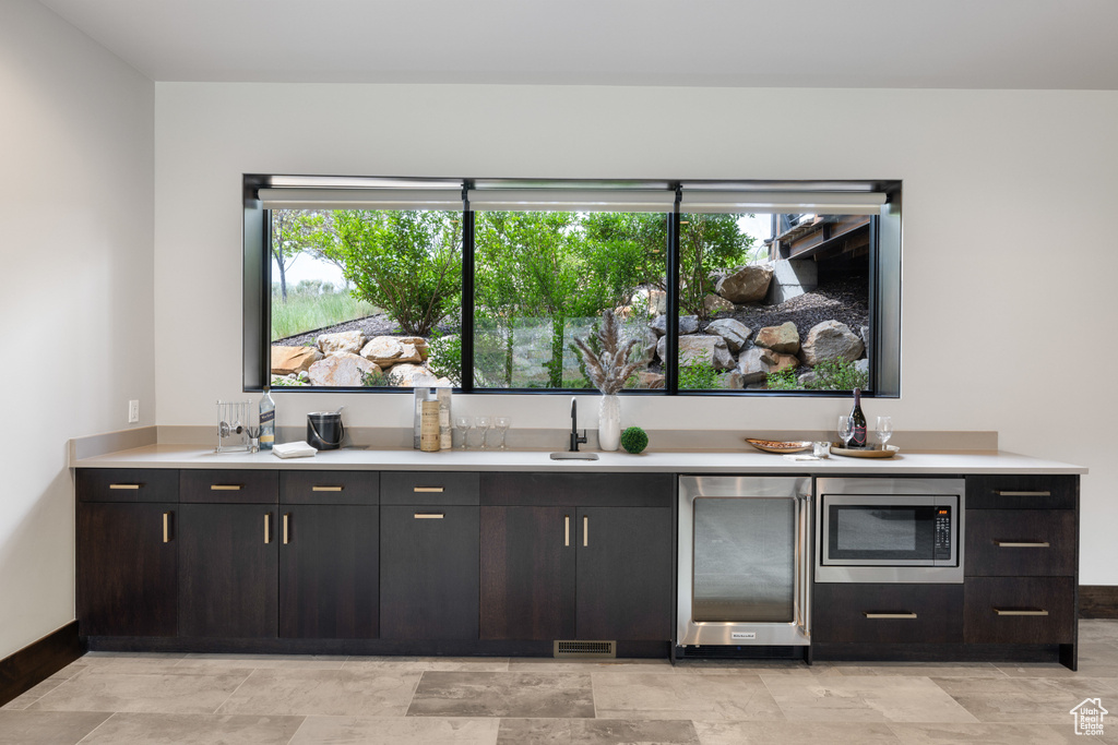 Bar with stainless steel microwave, plenty of natural light, baseboards, and refrigerator