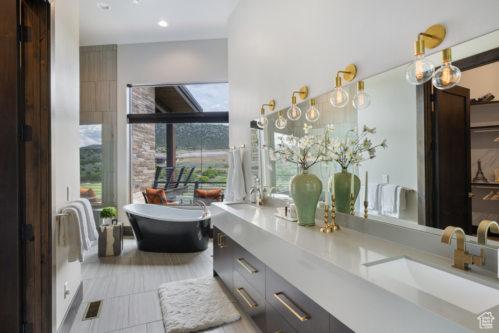Bathroom with double vanity, a soaking tub, tile patterned flooring, and recessed lighting