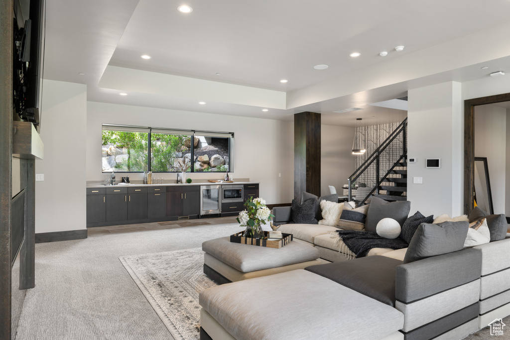 Living area featuring stairway, wine cooler, light colored carpet, bar with sink, and recessed lighting