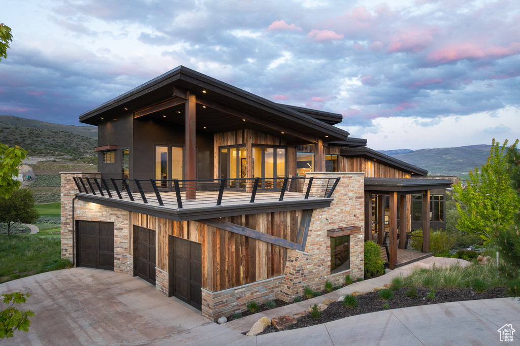 View of front of home featuring a balcony, driveway, a mountain view, and a garage
