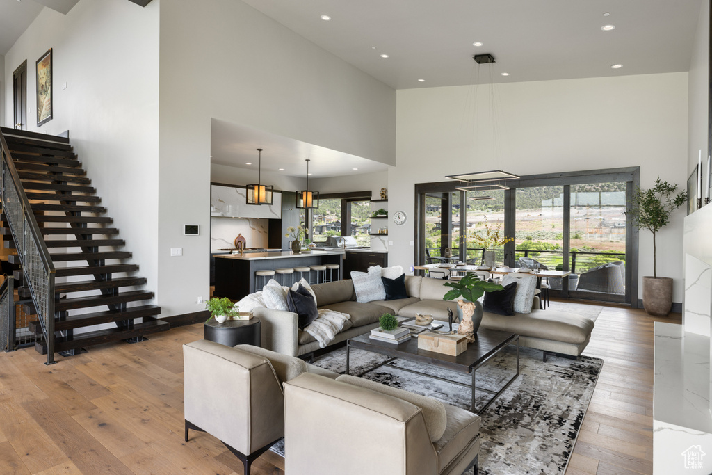 Living area featuring a high ceiling, light wood-style floors, recessed lighting, and stairs