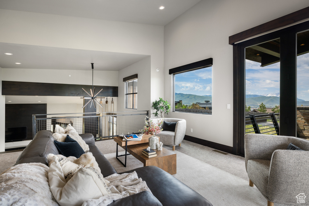 Carpeted living room featuring a chandelier, healthy amount of natural light, baseboards, a mountain view, and recessed lighting
