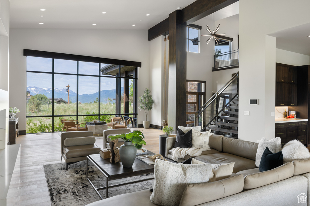 Living area with a high ceiling, light wood-type flooring, plenty of natural light, a mountain view, and stairway