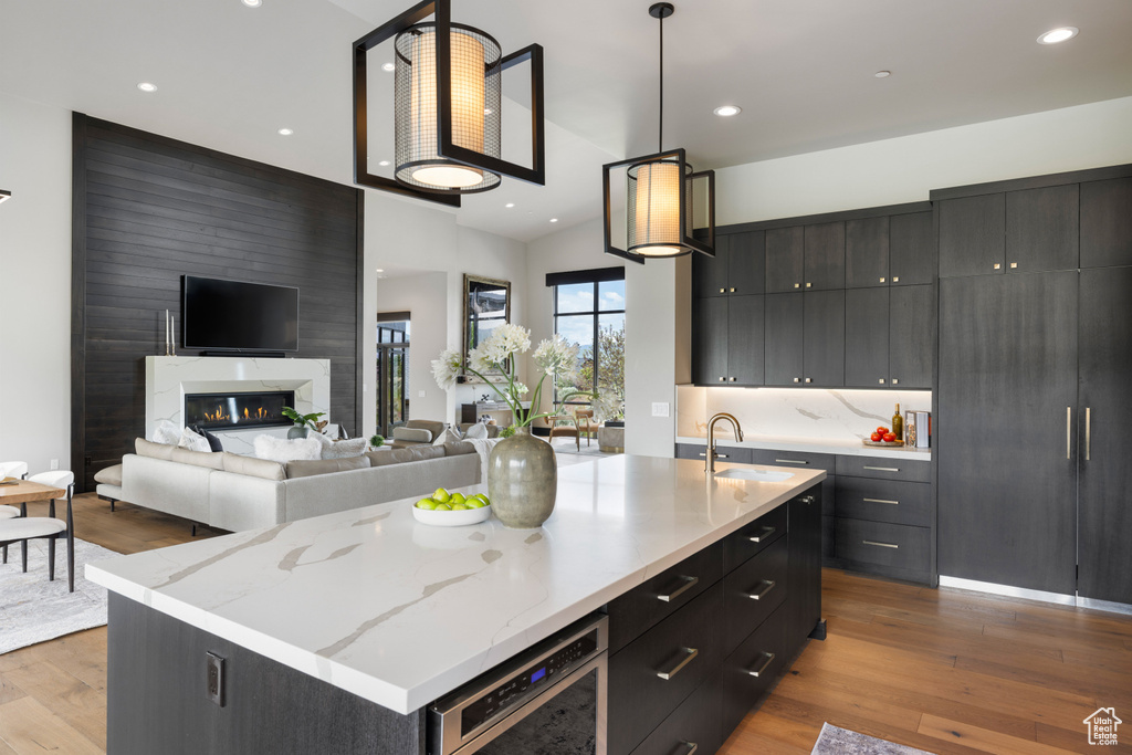 Kitchen featuring a sink, dark cabinets, wood finished floors, and recessed lighting