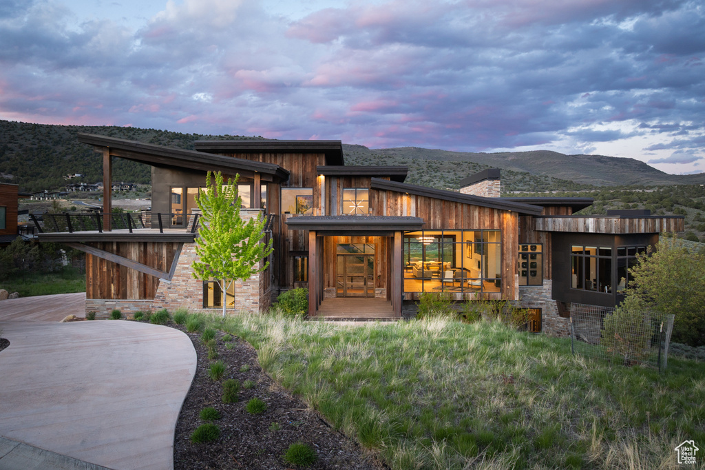 Back of property at dusk with stone siding, a chimney, and a mountain view
